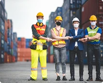 Diverse team of construction, logistics, and business professionals standing together at a shipping yard, representing workplace collaboration, safety, and cross-functional teamwork.