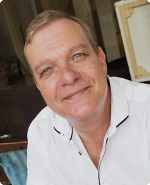 Professional headshot of a smiling business executive wearing a white shirt, representing approachable leadership and corporate expertise.